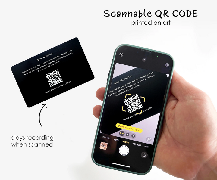 a hand holding a smartphone with a QR code printed on the screen, and a printed card with a QR code next to it.